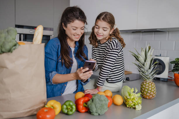 Mother and daughter returning home from groceries shopping Mother and daughter are at home, they are unpacking groceries delivering groceries to family stock pictures, royalty-free photos & images