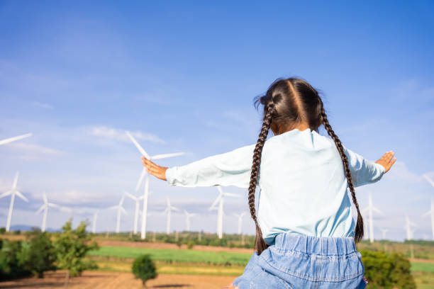 Wind turbines are an alternative electricity source to be sustainable resources in the future. People in the community with wind generators turbines. Clean energy concept saves the world stock photo