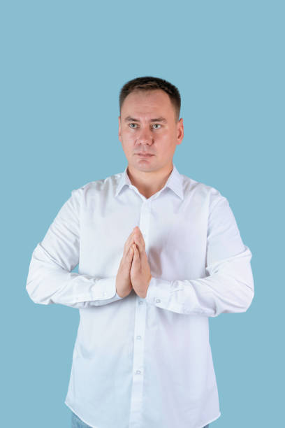 istock A man in a white shirt prays with his palms folded standing on a blue background 1355668592