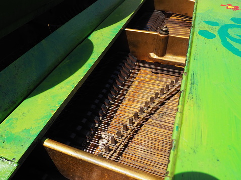 Strings, soundboard and piano mechanics. Piano on the street. Piano painted green. Performance of a piece of music. Street concert on a summer sunny day