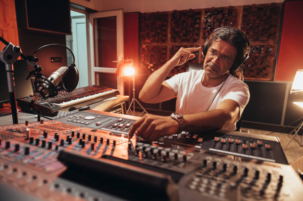 istock Senior hispanic music producer working on a mixing soundboard while in his studio 1355671512