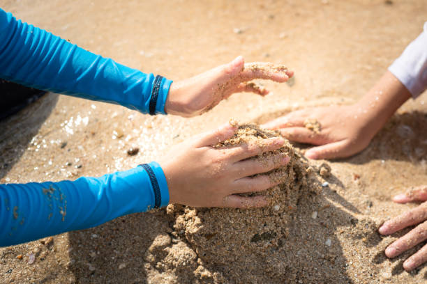 kinderhand spielt sand auf dem strandboden - erholungsaktivität. - sandbox child human hand sand stock-fotos und bilder
