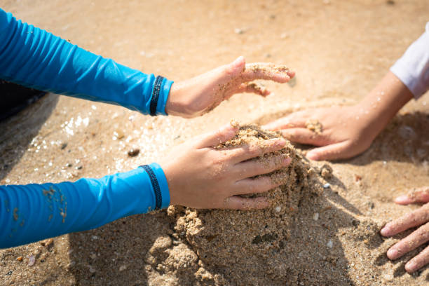 kid hand is playing sand on beach ground - recreation activity. - sandbox child human hand sand imagens e fotografias de stock