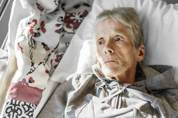 Sick, elderly senior woman in a hospital bed stock photo