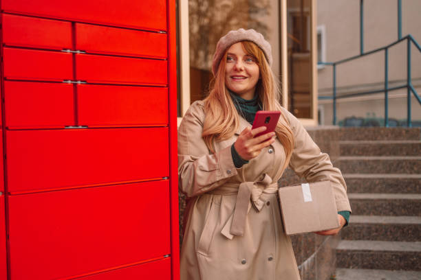 istock Woman picks up mail from automated self-service post terminal machine. Freight transportation. Express delivery 1355677632