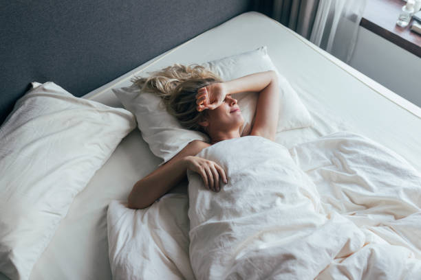 istock A Blonde Woman Lying In Her Bed Covered With A Blanket 1355681587