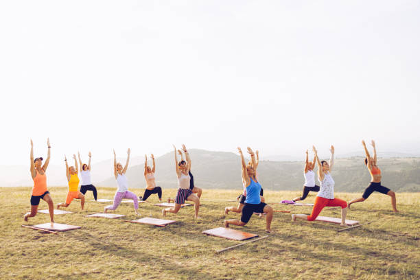 gruppo di donne che frequentano lezioni di yoga all'aperto - yoga exercising outdoors group of people foto e immagini stock