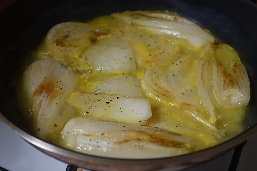 Endives and fennels in portions being cooked in a pan with orange juice