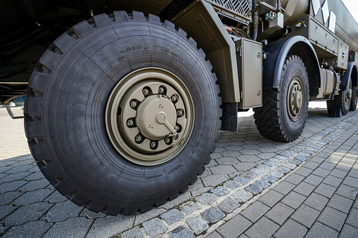 Large military grade tires on green gray army vehicle, closeup detail.