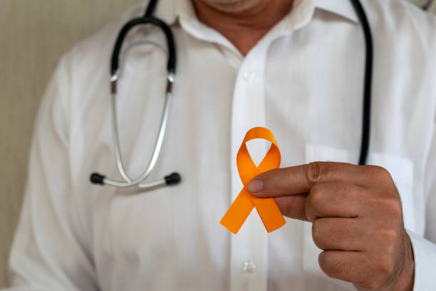 lekarz trzymający pomarańczową wstążkę. kampania zapobiegająca rakowi skóry, czerniakowi, grudniowa pomarańcza - kidney cancer zdjęcia i obrazy z banku zdjęć