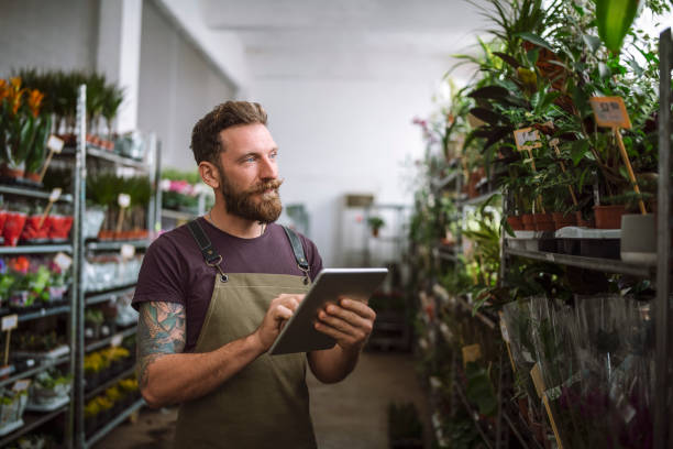 istock Man Working In A Flower Shop And Using Digital Tablet 1355688824