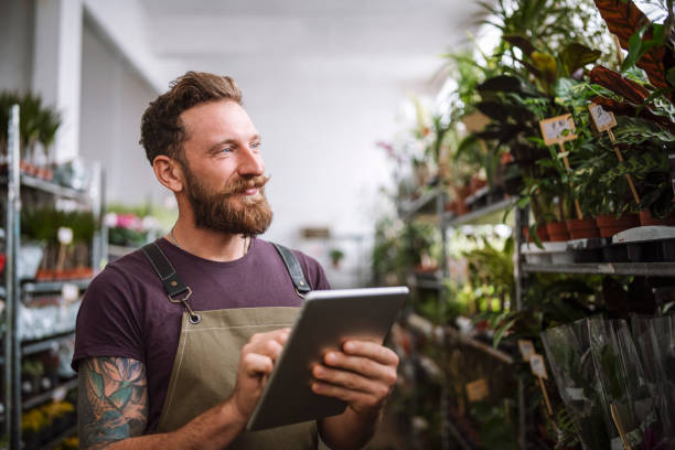 istock Man Working In A Flower Shop And Using Digital Tablet 1355688833