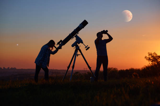 casal observando estrelas junto com um telescópio astronômico, olhando para planetas, estrelas, eclipse lunar e chuva de meteoros. - telescópio astronômico - fotografias e filmes do acervo