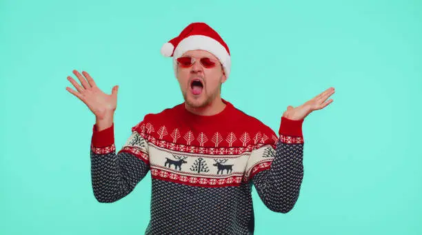 Photo of Man in Christmas sweater listening music via earphones, dancing disco fooling around having fun