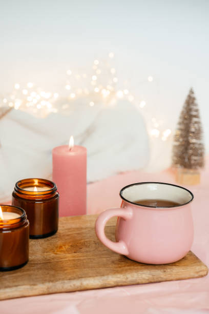 istock a cup with tea and three candles on a wooden table against a background with girlands. festive mood. merry christmas and happy new year. 1355692550