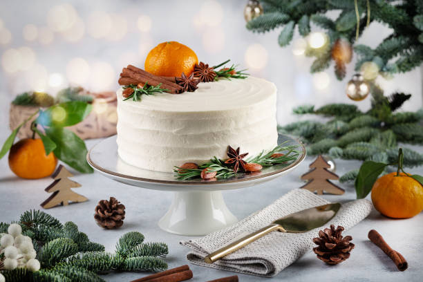 Christmas white cake decorated with tangerine, cinnamom sticks Christmas white cake decorated with tangerine, cinnamom sticks on a white background with a Christmas decoration or winter holidays pastry food concept. christmas cake stock pictures, royalty-free photos & images