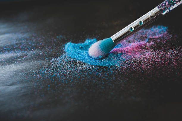 istock Makeup brush and shiny pink and blue sequins on a black background. Festive magic makeup concept. Template for design, top view Flat Lay Copy space. 1355693547
