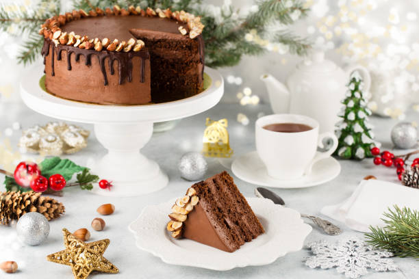 gâteau au chocolat de noël décoré de noix sur fond blanc avec un arbre de noël et des lumières - tea cake photos et images de collection