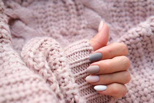 暖かいニットセーターで美しいマットオーバルマニキュアと女性の手。冬のトレンド、ゲルポリッシュ、シェラックでベージュの爪を磨きます。スペースをコピーします。 - 手の爪 ストックフォトと画像