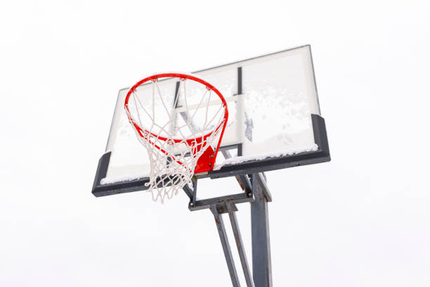 istock Red basketball hoop on a backboard on a light background, bottom view. 1355695158