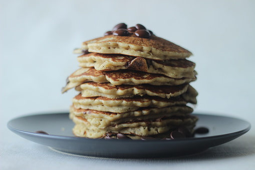 Stack of Oats Choco chips pancakes along with coffee for breakfast. Healthy pancakes made of oats flour loaded with chocolate chips. Shot on white background