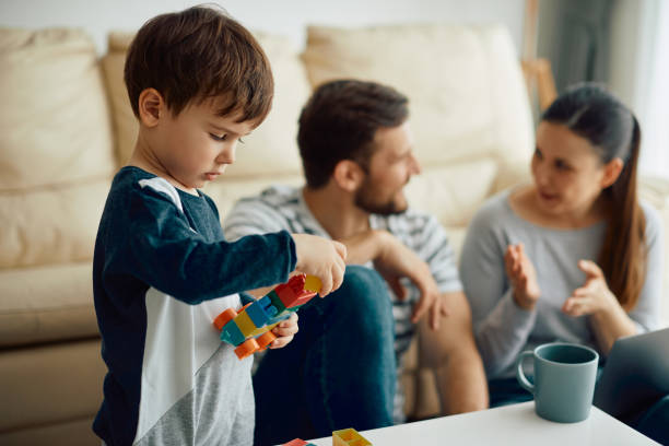 istock Small boy playing with toy block while being with his parents at home. 1355696161