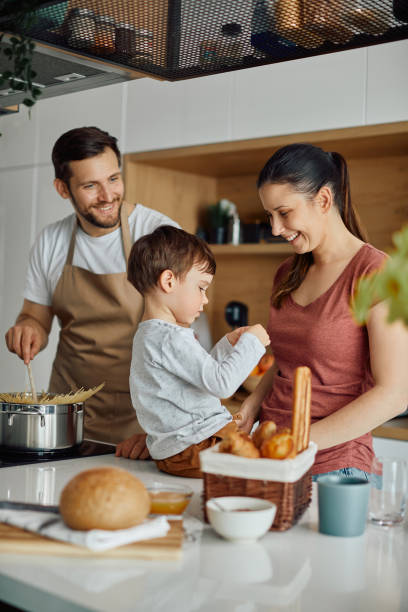キッチンで食事を準備しながら楽しんで幸せな家族。 - mother son family cooking ストックフォトと画像