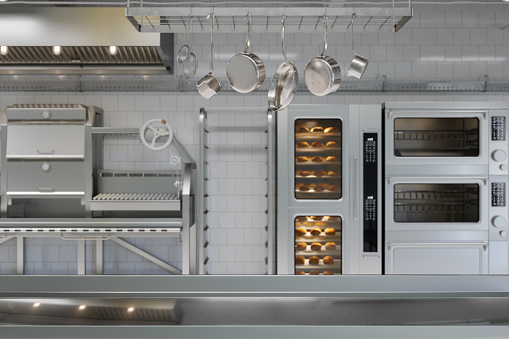 Superficie metálica vacía y cocina industrial borrosa con utensilios de cocina, equipos y productos de panadería. photo
