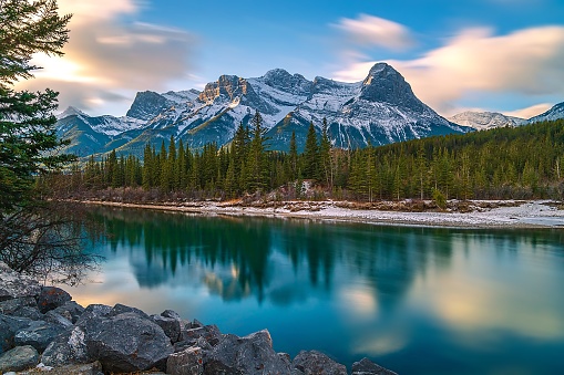 A panoramic long exposure of mountains and Bow river in Canmore.