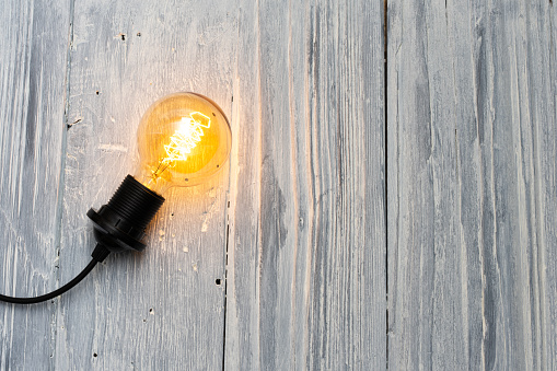 Light bulb on white wooden background