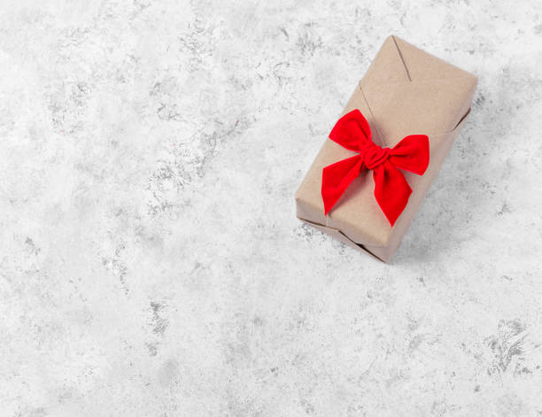 istock Gift box in craft paper with a red bow on a light gray background. 1355702041