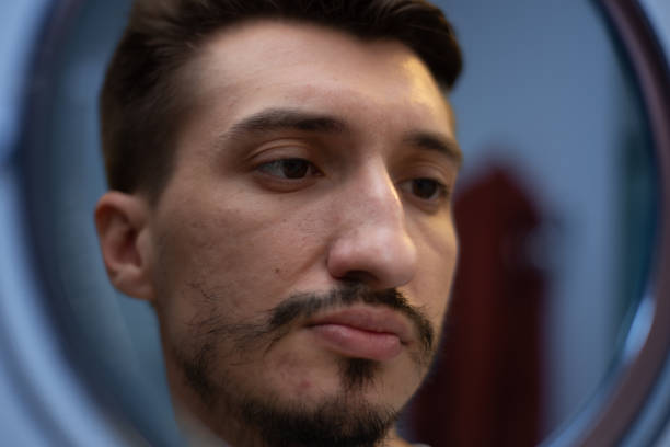 The guy with the rare beard looks in the bathroom mirror in a touched way