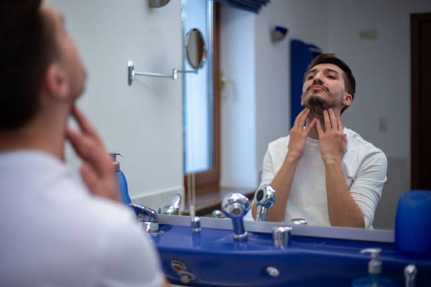 istock A guy with a patchy beard looks in the mirror 1355702851