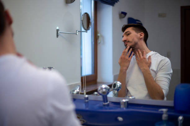 istock A guy with a patchy beard looks in the mirror 1355702855