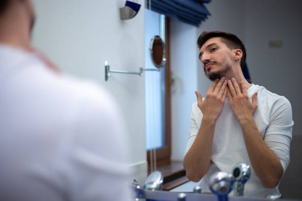 istock A guy with a patchy beard looks in the mirror 1355702881