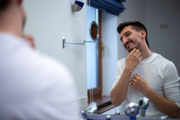 istock A guy with a patchy beard looks in the mirror 1355702889