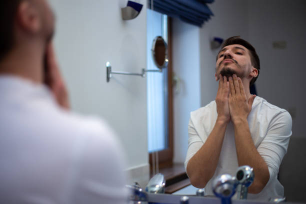 istock A guy with a patchy beard looks in the mirror 1355702928