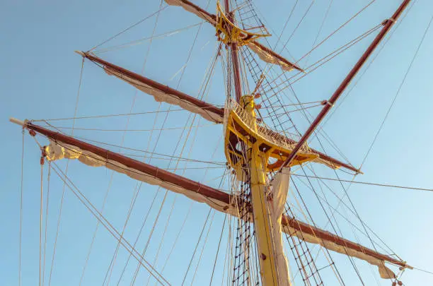 Mast sailing ship, with raised sails against the clear sky in calm weather.