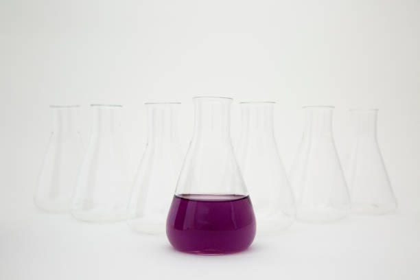istock Scientific laboratory glass erlenmeyer flask filled with purple liquid with glassware equipment on white background. 1355703947