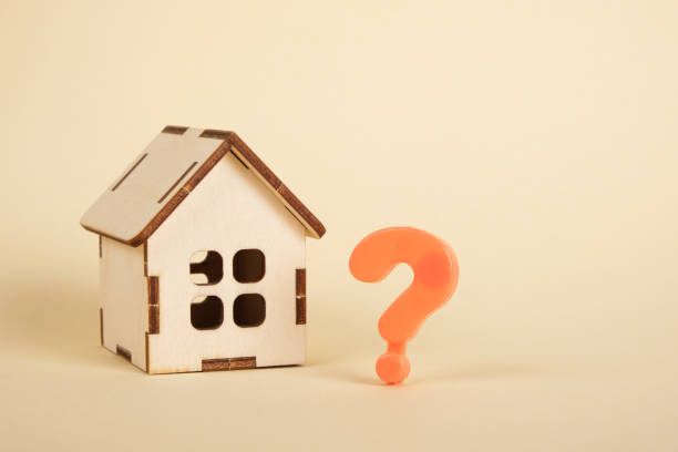 istock small wooden house model and a question mark on a beige background 1355705262