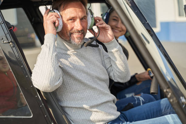 istock Cheerful helicopter pilot taking lady for a flight 1355710026