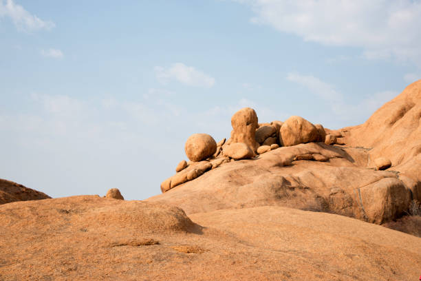 A stunning daytime perspective of the Golden Rock region in Tabuk. The historic red rocks, glistening desert sand, and clear blue skies combine to form a picturesque landscape.