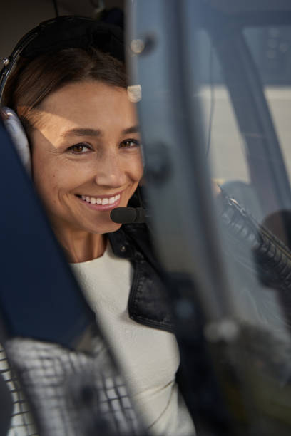istock Joyful woman in safety headset posing in copter cockpit 1355710140