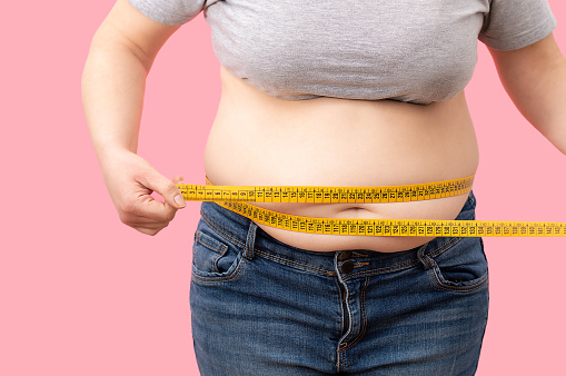 Chica gorda con sobrepeso comprobando su peso photo