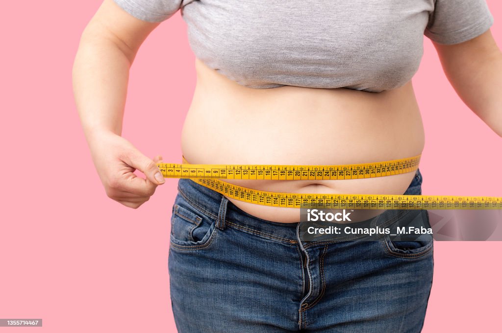 Fat girl with overweight checking out his weight Fat girl with overweight checking out his weight isolated on white background Obesity Stock Photo