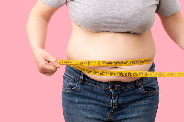 Fat girl with overweight checking out his weight Fat girl with overweight checking out his weight isolated on white background excess fat stock pictures, royalty-free photos & images