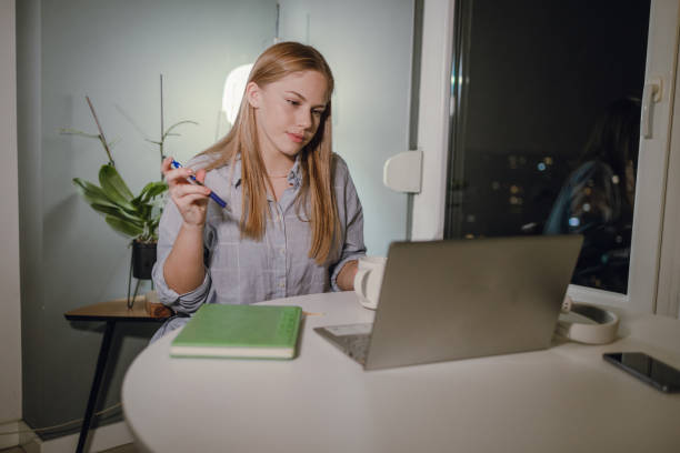 istock Young woman working late at home on laptop 1355716554