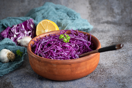 Sliced red cabbage with apple. Delicious salad with Christmas meat. Stock photo on grey-blue background