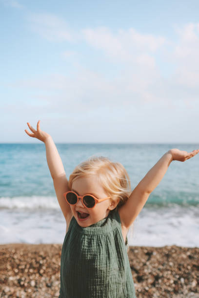 enfant heureux fille jouant sur la plage émotionnelle bambin en lunettes de soleil 3 ans enfant levé mains en famille voyage style de vie vacances en plein air - 2 3 years photos et images de collection
