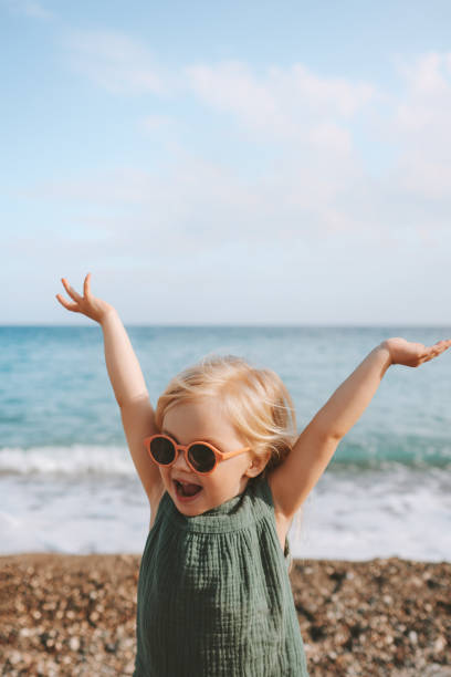 happy child girl playing on beach emotional toddler in sunglasses 3 years old kid raised hands family travel lifestyle vacations outdoor - 2 3 years fotos imagens e fotografias de stock